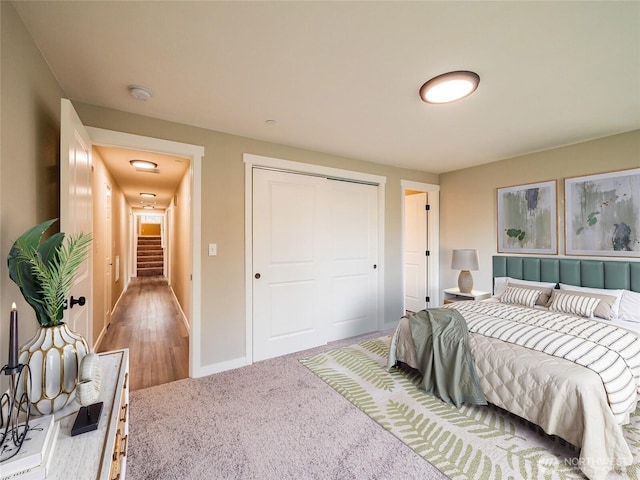 carpeted bedroom featuring baseboards and a closet