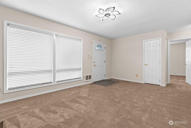 foyer with carpet floors and a textured ceiling