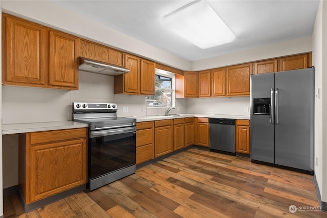 kitchen with sink, stainless steel appliances, dark hardwood / wood-style flooring, and extractor fan