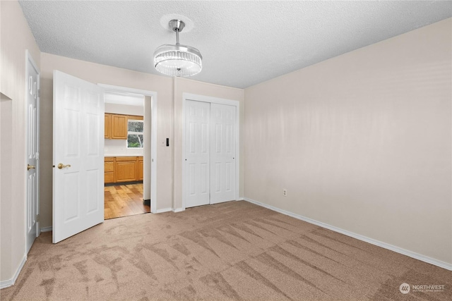 unfurnished bedroom featuring light colored carpet, a closet, and a textured ceiling