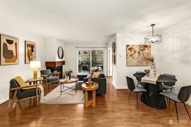 living area featuring hardwood / wood-style flooring, a multi sided fireplace, and a notable chandelier