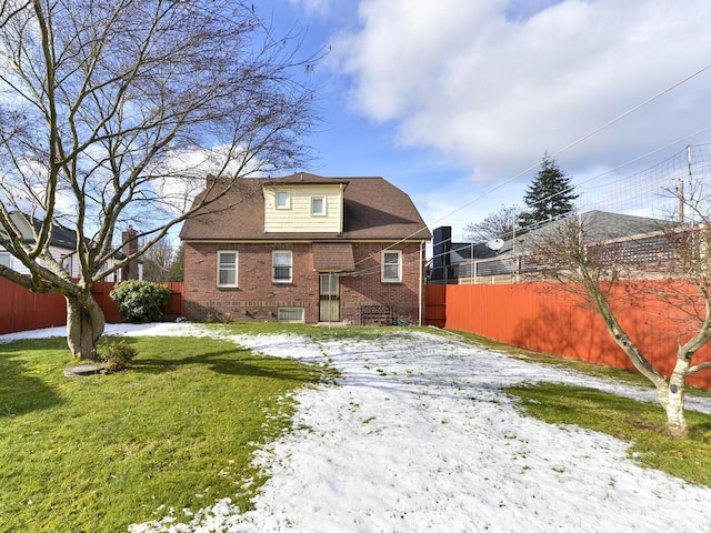 snow covered rear of property with a yard