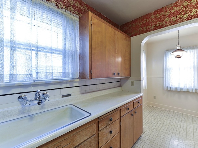 kitchen with sink, decorative backsplash, a wealth of natural light, and hanging light fixtures