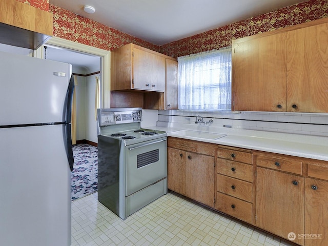 kitchen with white range with electric stovetop, sink, backsplash, and stainless steel refrigerator