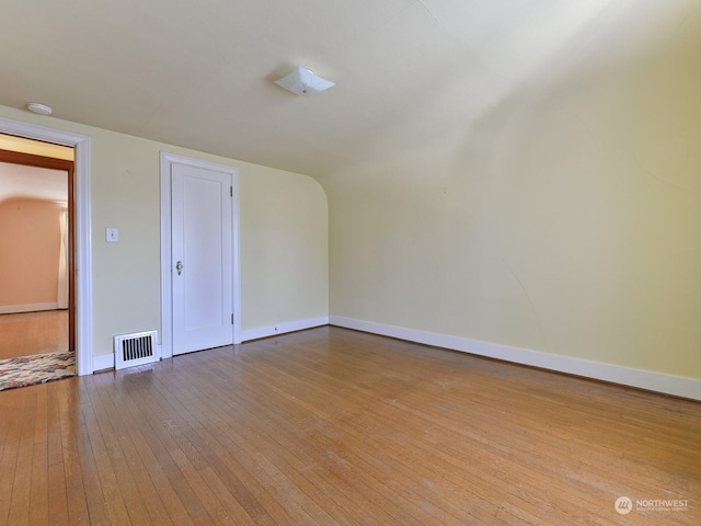 spare room featuring lofted ceiling and light wood-type flooring