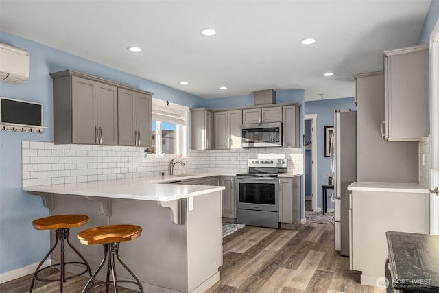 kitchen featuring stainless steel appliances, gray cabinets, and kitchen peninsula