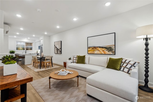 living room featuring sink, a wall mounted air conditioner, and light wood-type flooring