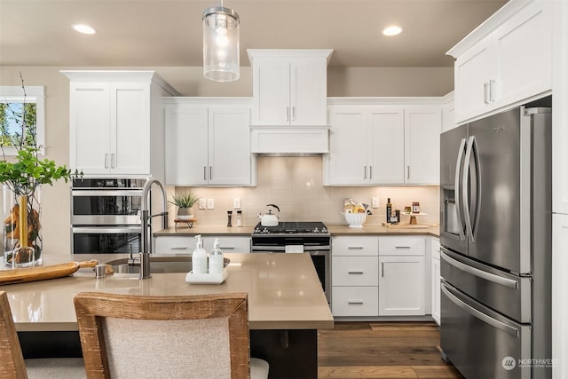 kitchen with stainless steel appliances, pendant lighting, white cabinets, and decorative backsplash