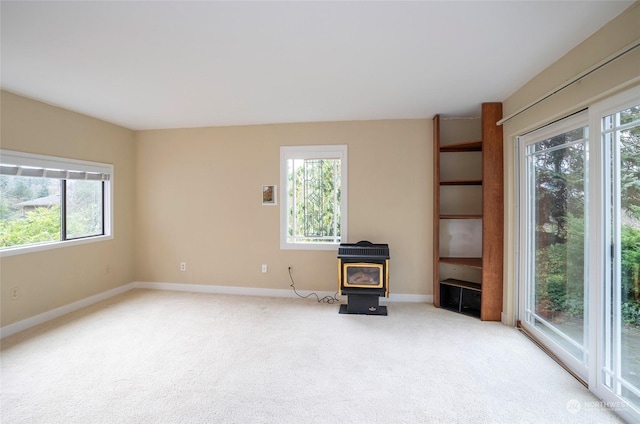 unfurnished living room featuring light colored carpet and a wood stove