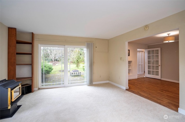 unfurnished living room featuring carpet and a wood stove