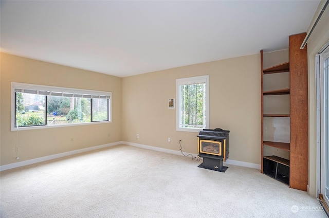 unfurnished living room featuring a wood stove and light colored carpet