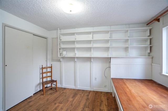 laundry area with dark hardwood / wood-style floors and a textured ceiling