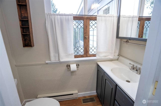 bathroom with vanity, baseboard heating, and toilet