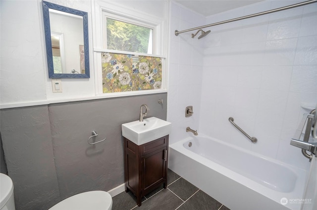 full bathroom featuring vanity, tiled shower / bath, tile patterned floors, and toilet