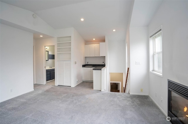 unfurnished living room with vaulted ceiling and light carpet