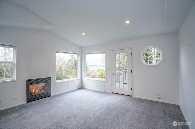 unfurnished living room featuring vaulted ceiling, carpet, and plenty of natural light