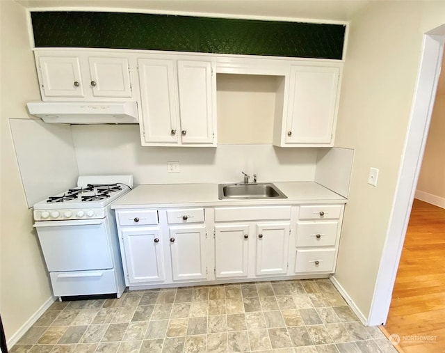 kitchen with sink, white gas stove, and white cabinets