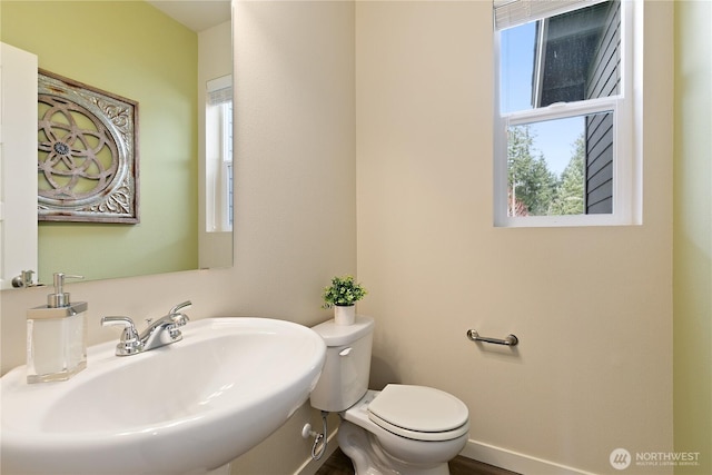 bathroom featuring baseboards, a sink, and toilet