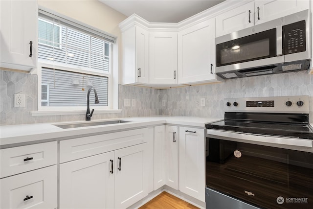 kitchen featuring sink, white cabinets, decorative backsplash, stainless steel appliances, and light hardwood / wood-style flooring