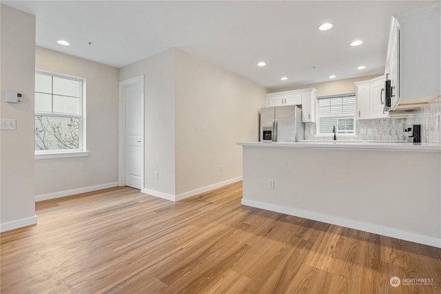 kitchen featuring stainless steel fridge with ice dispenser, backsplash, light hardwood / wood-style flooring, and white cabinets