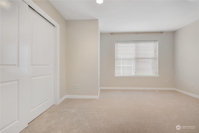 unfurnished bedroom with light colored carpet and a closet