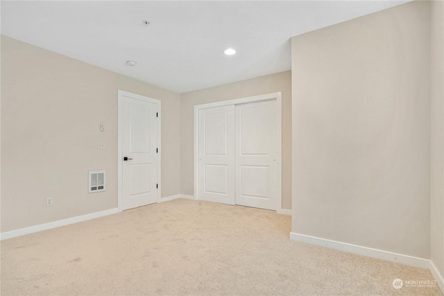 unfurnished bedroom featuring light colored carpet and a closet