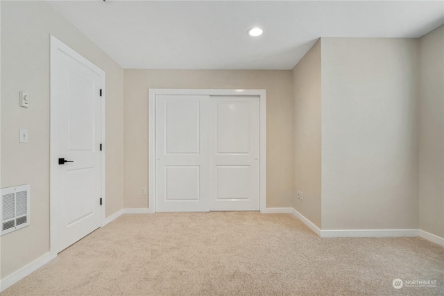 unfurnished bedroom with light carpet and a closet