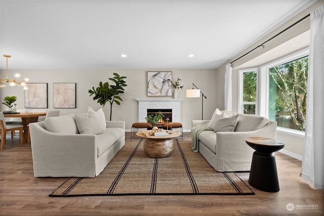 living room with an inviting chandelier, a brick fireplace, and light hardwood / wood-style flooring