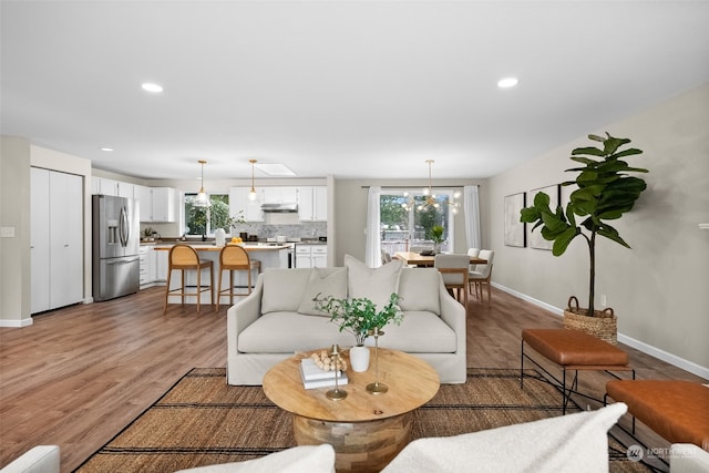 living room with wood-type flooring, plenty of natural light, and a notable chandelier