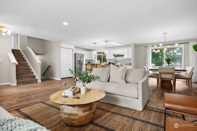 living room featuring wood-type flooring, a wealth of natural light, and a notable chandelier