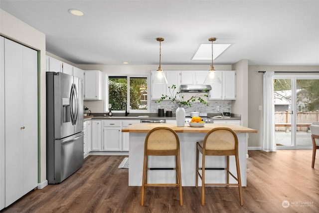 kitchen with dark wood-type flooring, white cabinetry, decorative light fixtures, stainless steel fridge with ice dispenser, and a kitchen island