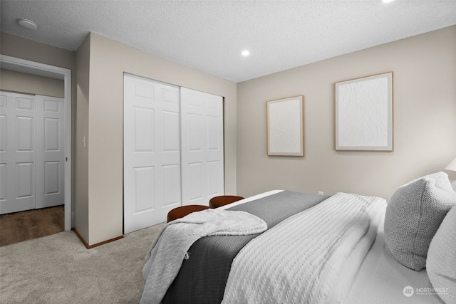 carpeted bedroom featuring a textured ceiling and a closet