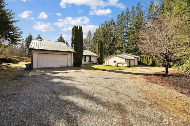 exterior space featuring a garage, metal roof, and an outdoor structure