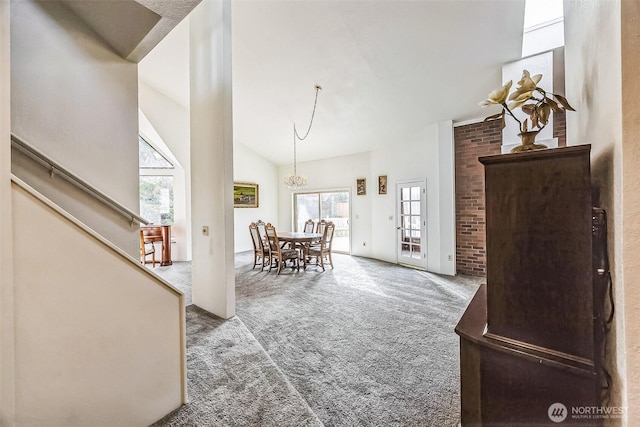 carpeted dining space featuring high vaulted ceiling, stairway, and an inviting chandelier