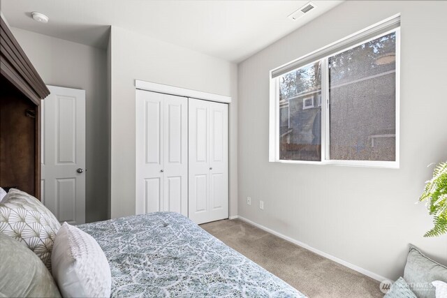 carpeted bedroom with a closet, visible vents, and baseboards