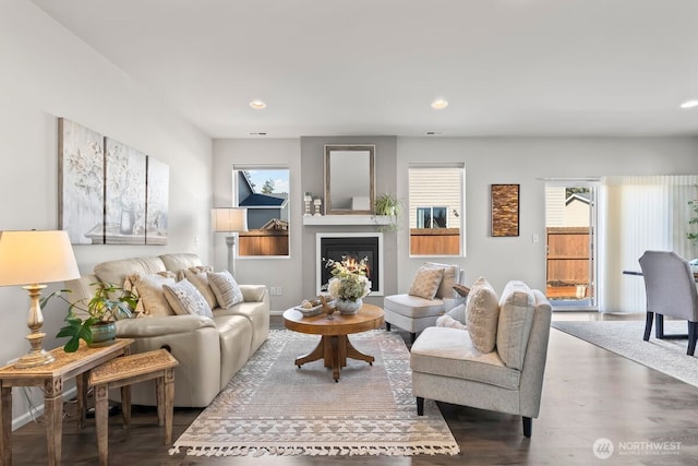 living area featuring recessed lighting, wood finished floors, and a glass covered fireplace