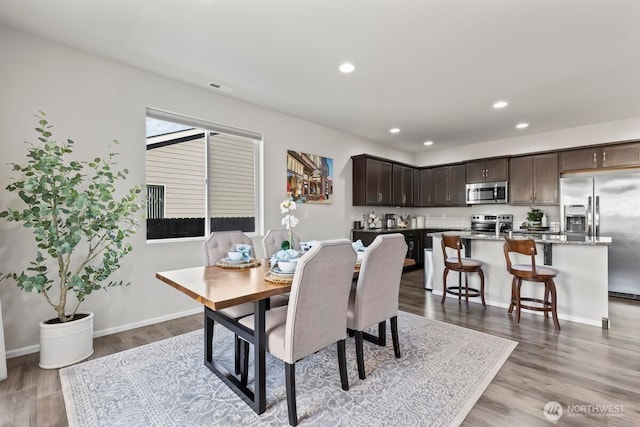 dining room featuring baseboards, wood finished floors, visible vents, and recessed lighting