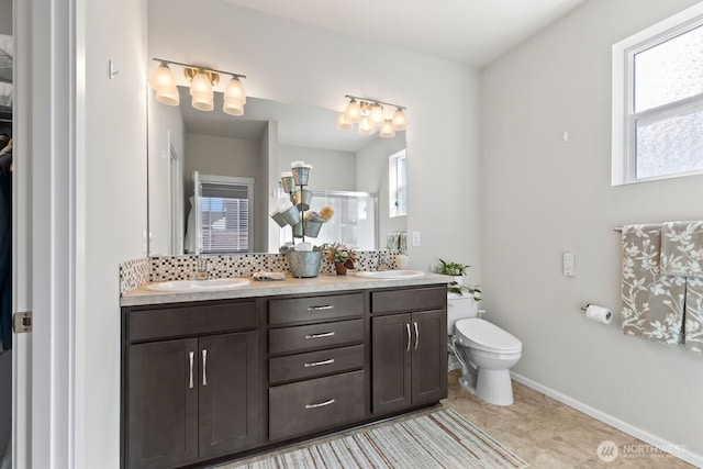 bathroom with a healthy amount of sunlight, a sink, decorative backsplash, and double vanity