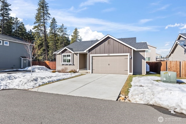 view of front of home with driveway, board and batten siding, an attached garage, and fence