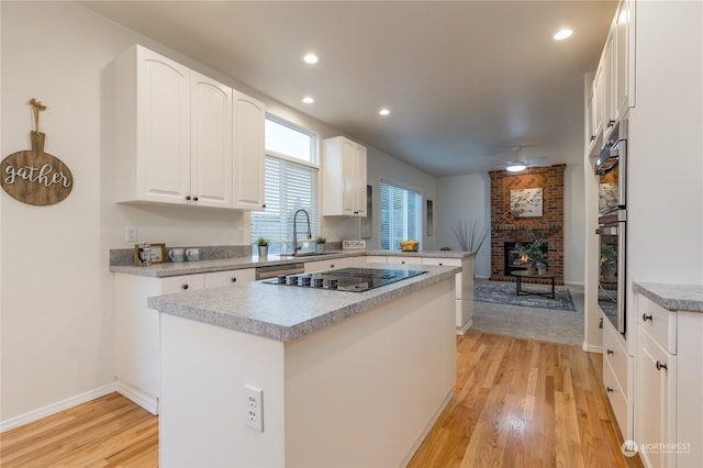 kitchen with black electric stovetop, sink, white cabinets, and a kitchen island