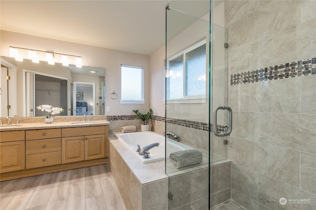 bathroom featuring shower with separate bathtub, hardwood / wood-style floors, and vanity