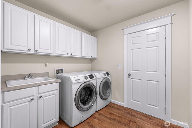 laundry room featuring washing machine and clothes dryer, a sink, baseboards, cabinet space, and dark wood finished floors