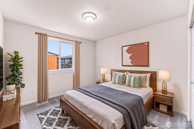 bedroom with baseboards, visible vents, and light colored carpet