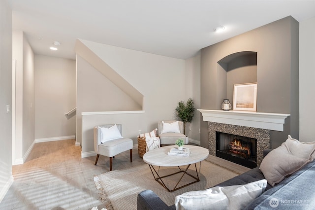 living room with a tiled fireplace and light wood-type flooring