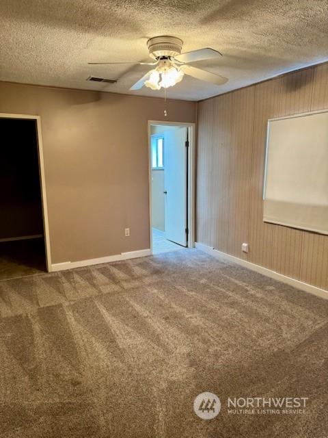 carpeted empty room with ceiling fan and a textured ceiling