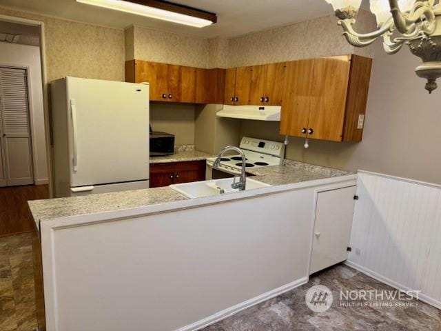 kitchen featuring sink, white appliances, kitchen peninsula, and a chandelier