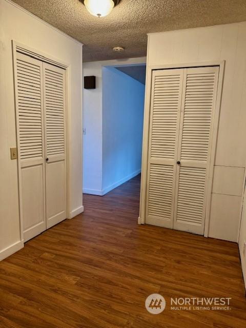 hallway featuring dark wood-type flooring and a textured ceiling