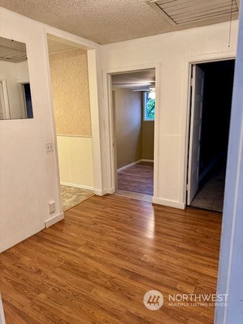 hall with hardwood / wood-style floors and a textured ceiling