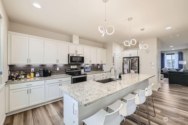 kitchen with white cabinetry, sink, stainless steel appliances, and hanging light fixtures