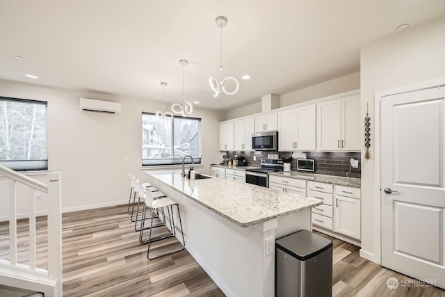 kitchen with white cabinetry, appliances with stainless steel finishes, sink, and a wall mounted air conditioner